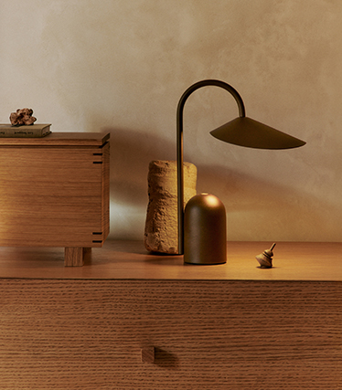 Lampe de table au design sculptural et élégant, illuminant un buffet en bois d’une lumière douce