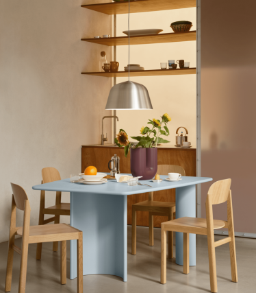 Coin repas minimaliste avec suspension, étagères en bois et table dressée.