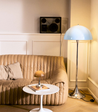 Lampadaire et lampe de table Panthella de Louis Poulsen dans un salon chaleureux avec canapé en cuir