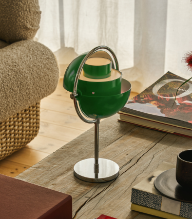 Lampe de table Multi-Lite verte au pied chromé sur une table en bois à côté de livres.